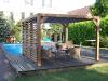 Carport BioClimatique en bois avec vantelles derrière une piscine