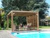 Pergola BioClimatique en bois avec vantelles derrière une piscine