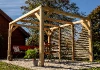 Pergola Bioclimatique en bois avec vantelles sur un côté devant un chalet de jardin